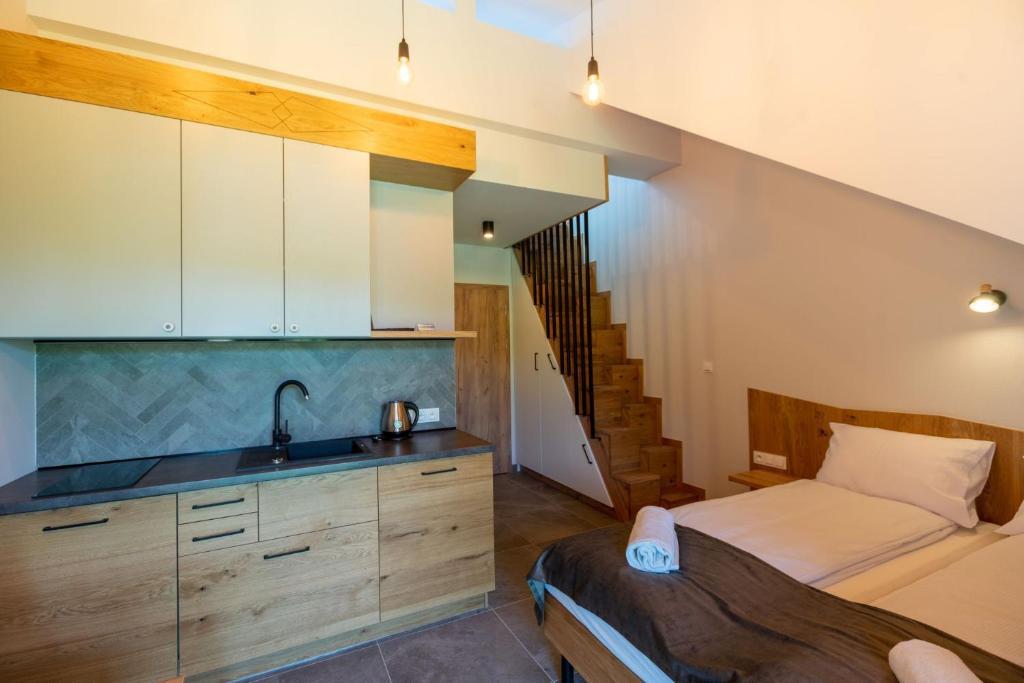 Compact studio with kitchenette, single bed, wooden staircase leading to mezzanine, cozy lighting.