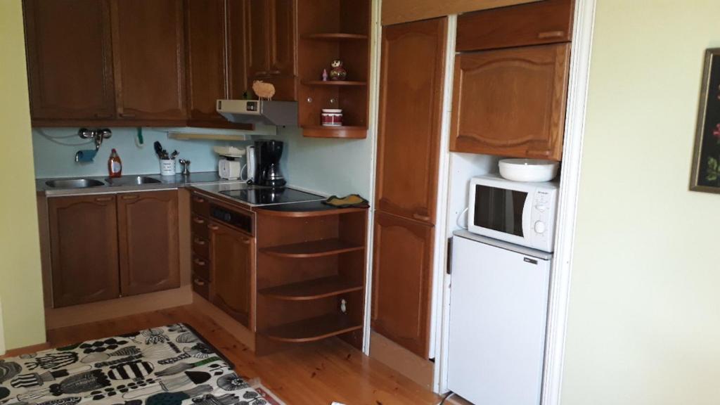 una pequeña cocina con armarios de madera y nevera blanca. en Studio mummola, en Varkaus