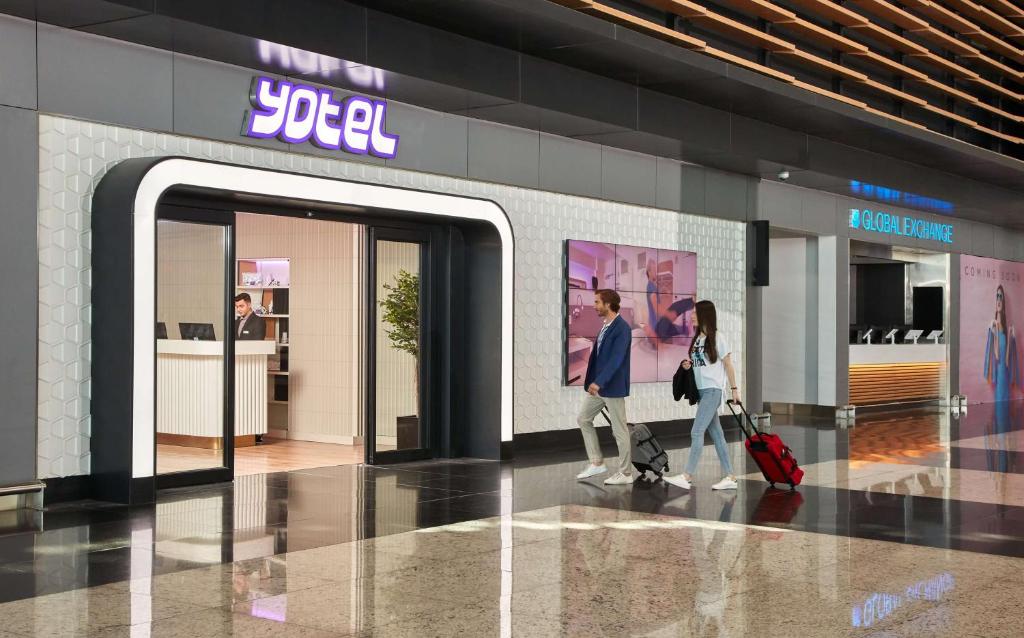 dwoje ludzi przechodzi przez drzwi w sklepie w obiekcie YOTEL Istanbul Airport, City Entrance w Stambule