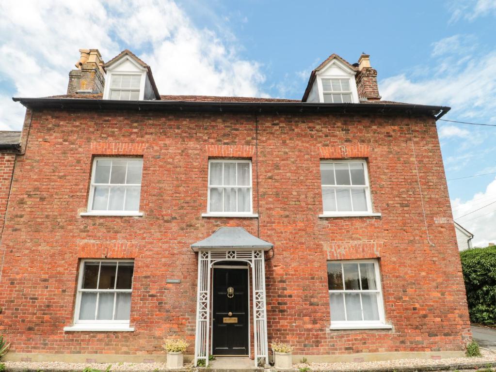 una vieja casa de ladrillo rojo con una puerta negra en Overton Cottage, en Sturminster Newton