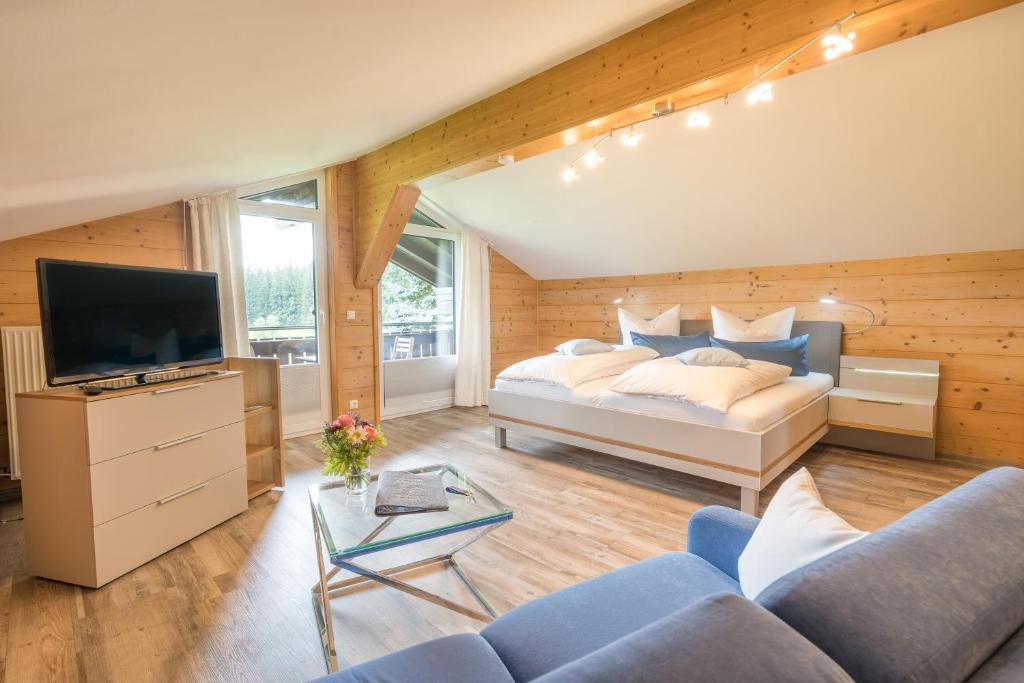 een slaapkamer met een bed en een tv en een bank bij Haus am Gaisalpbach in Oberstdorf