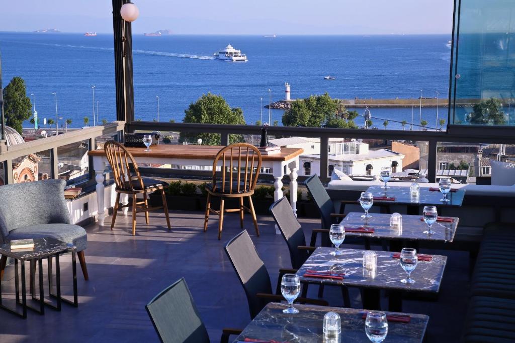 HOTEL BRONTE في إسطنبول: مطعم به طاولات وكراسي ومطل على المحيط