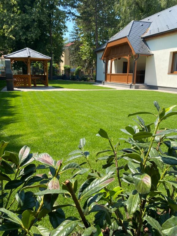 un jardín con cenador y un edificio en Karinthy ház, en Siófok