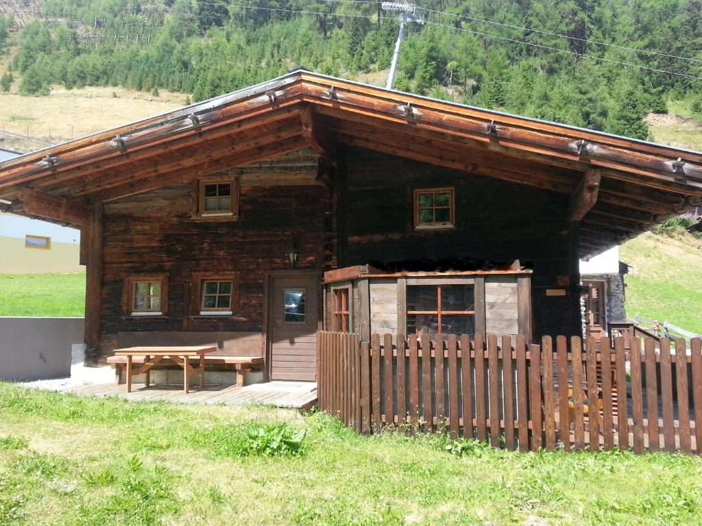 une cabane en rondins avec une clôture en bois devant elle dans l'établissement Hüttenzeit almhütte sölden, à Sölden