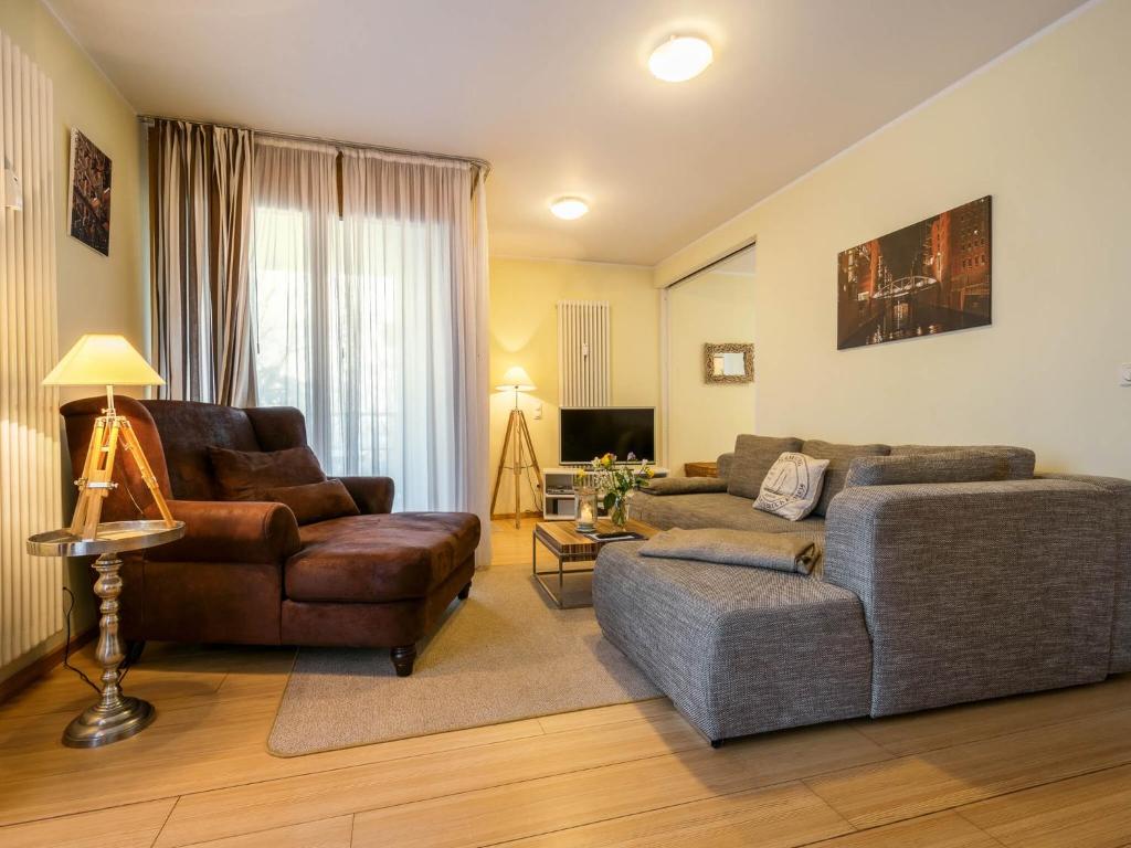 een woonkamer met een bank en een stoel bij Kaiservillen Heringsdorf - Ferienwohnung mit 1 Schlafzimmer und Terrasse D101 in Heringsdorf