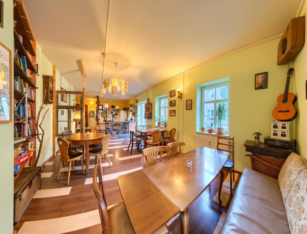 un soggiorno con tavoli, sedie e chitarra di Labyrinth Hostel Weimar a Weimar