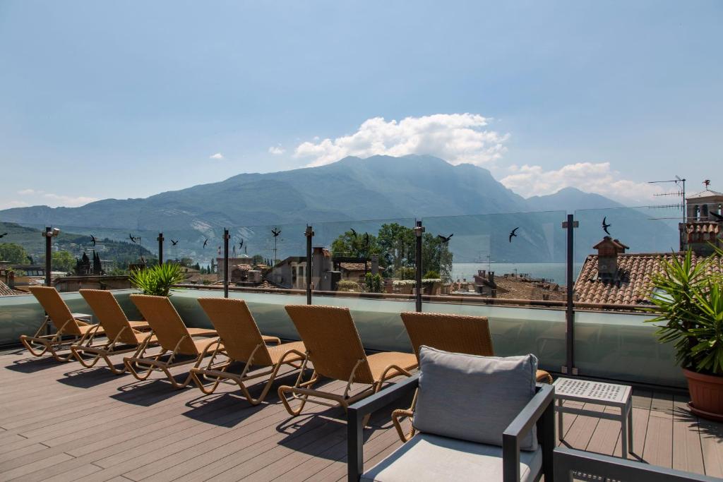a row of chairs sitting on a balcony with a mountain at Hotel Antico Borgo in Riva del Garda