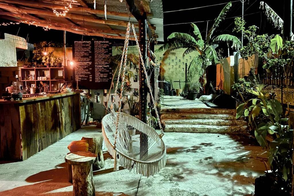 a swinging chair in a room with plants at Jungla Bacalar in Bacalar