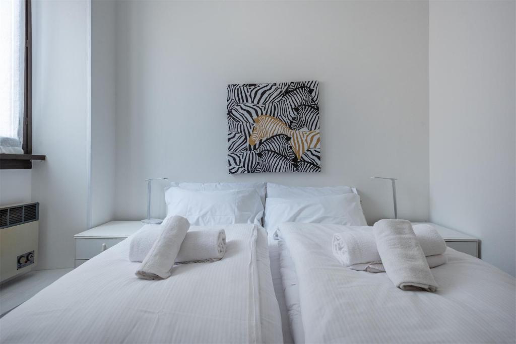a white bedroom with two white beds and a painting at Casa Anna in Riva del Garda