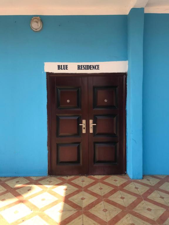 的住宿－BLUE RESIDENCE，蓝色墙上的棕色门,上面有标志