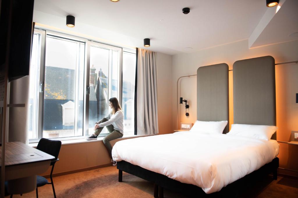 a woman sitting on a window sill in a hotel room at YOU Are Deauville in Deauville