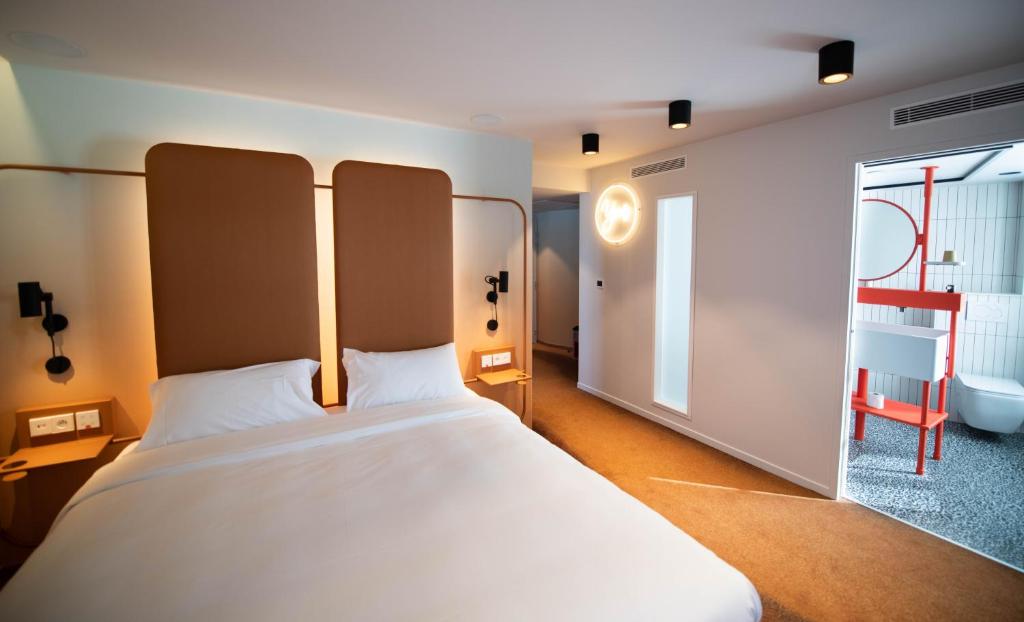 a bedroom with a large white bed and a window at YOU Are Deauville in Deauville
