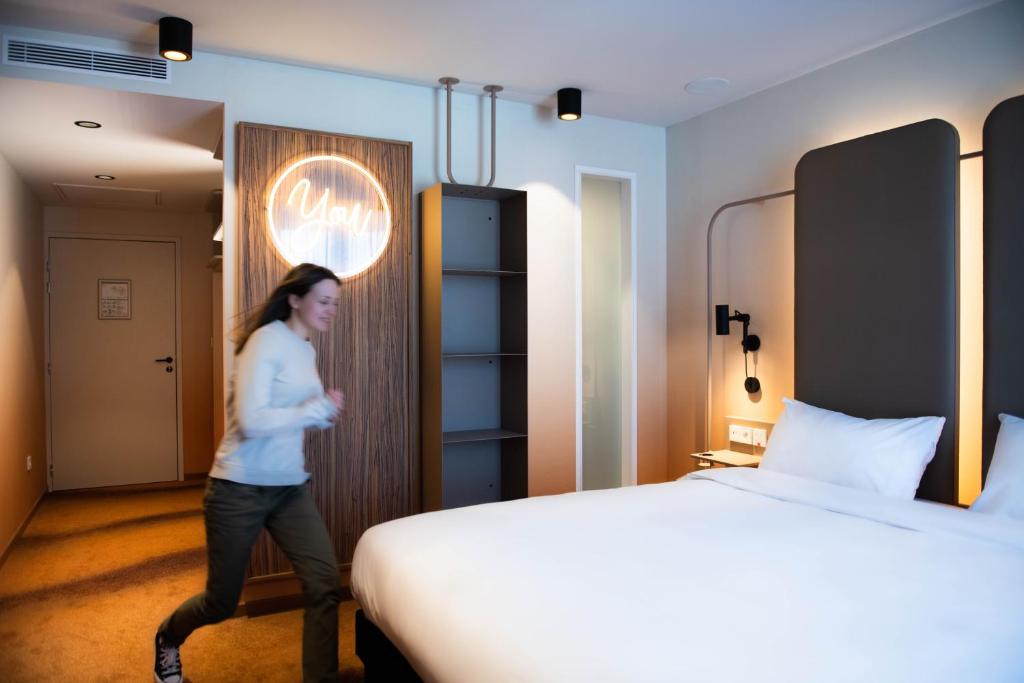 a woman walking through a hotel room with a bed at YOU Are Deauville in Deauville