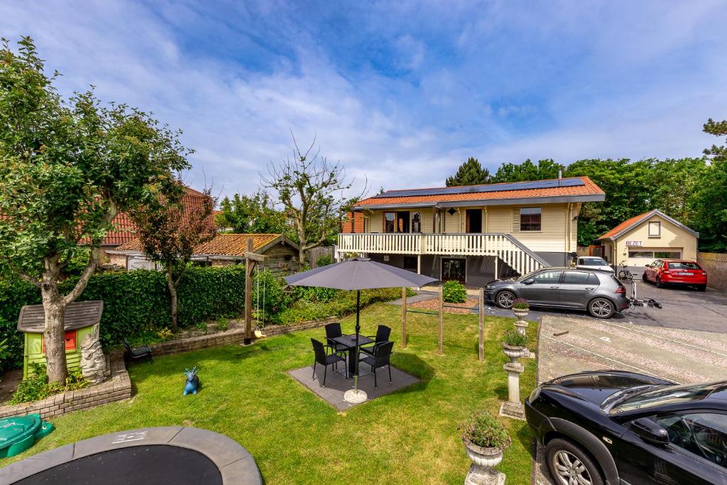 un patio con una mesa y una sombrilla frente a una casa en B&B Rehoboth en Domburg