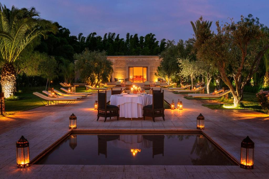 un patio con mesa y sillas junto a una piscina en Pavillon Terra Ababila en Exclusivité, en Marrakech