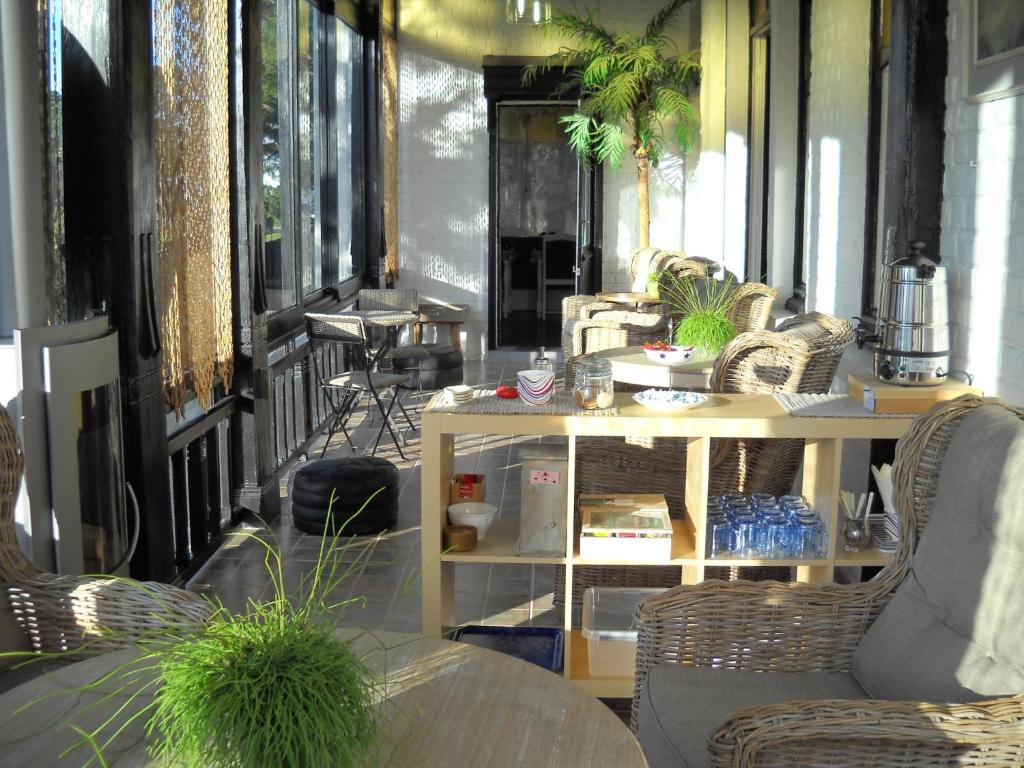 una veranda con sedie in vimini e tavolo di Hotel De Gouden Haan a De Haan