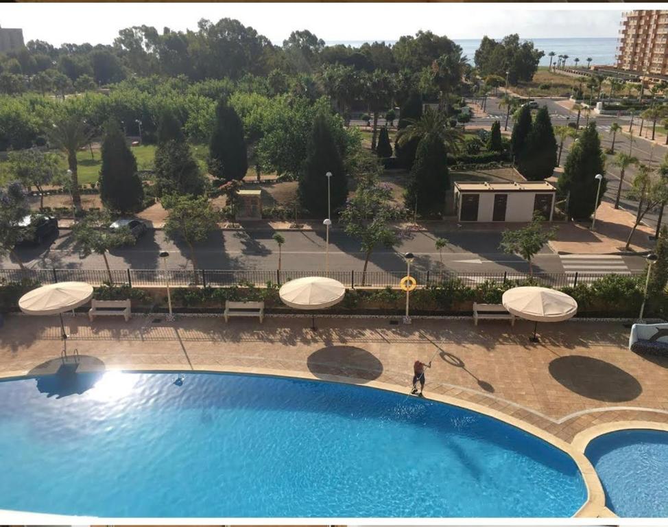 a person standing next to a swimming pool with umbrellas at Marina Dor holidays in Oropesa del Mar