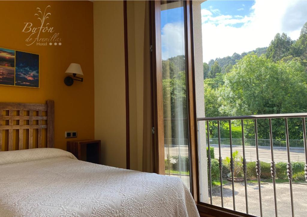 sypialnia z łóżkiem i dużym szklanym oknem w obiekcie Hotel Bufon de Arenillas w mieście Vidiago