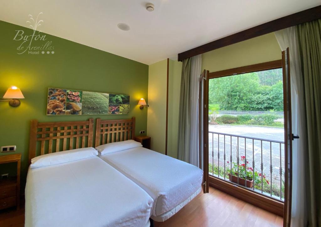a bedroom with a bed and a large window at Hotel Bufon de Arenillas in Vidiago