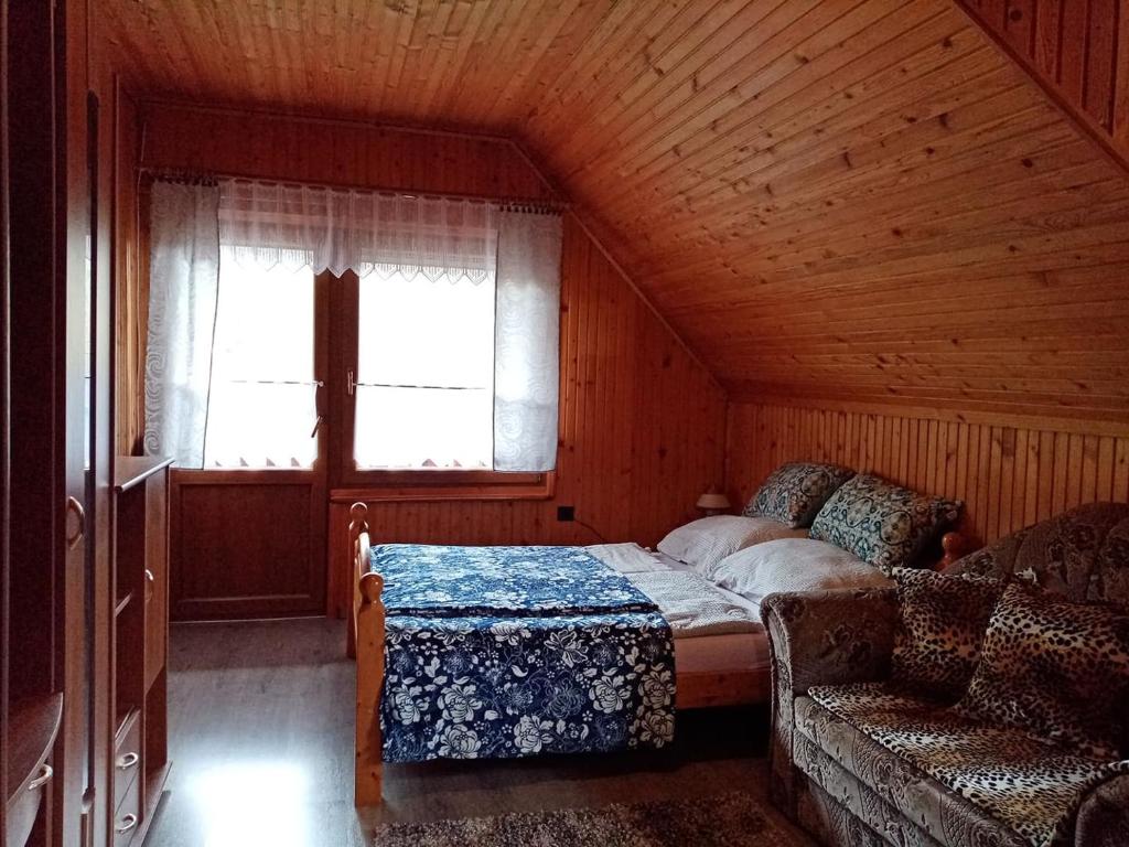 a bedroom with a bed and a window and a couch at Erdei Szalonka Vendégház in Háromhuta