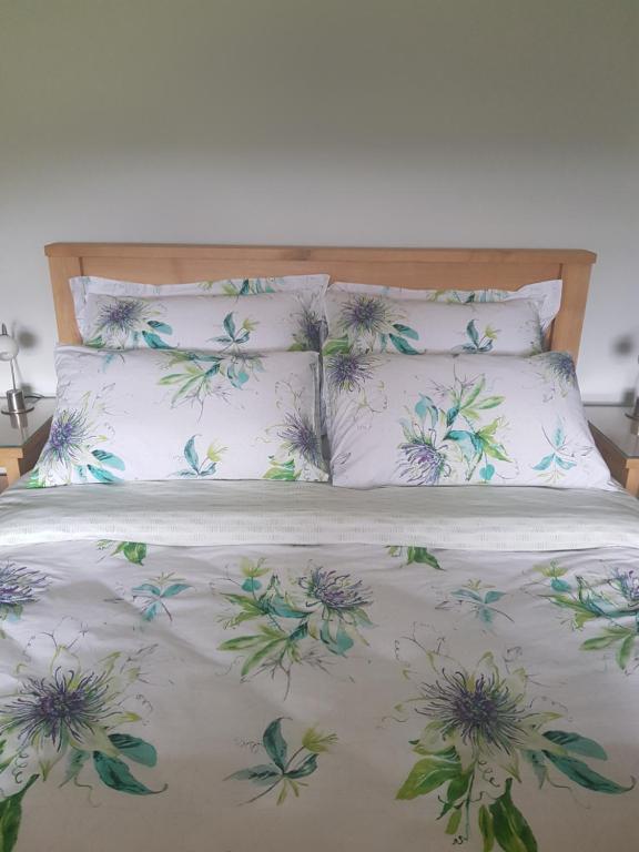 a bed with a white bedspread with flowers on it at Hawkshead Cottage in Glossop