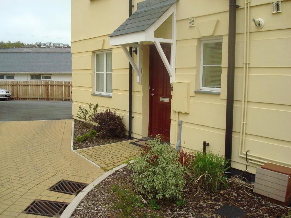 a yellow house with a red door next to a driveway at Riverside Apartment in Launceston