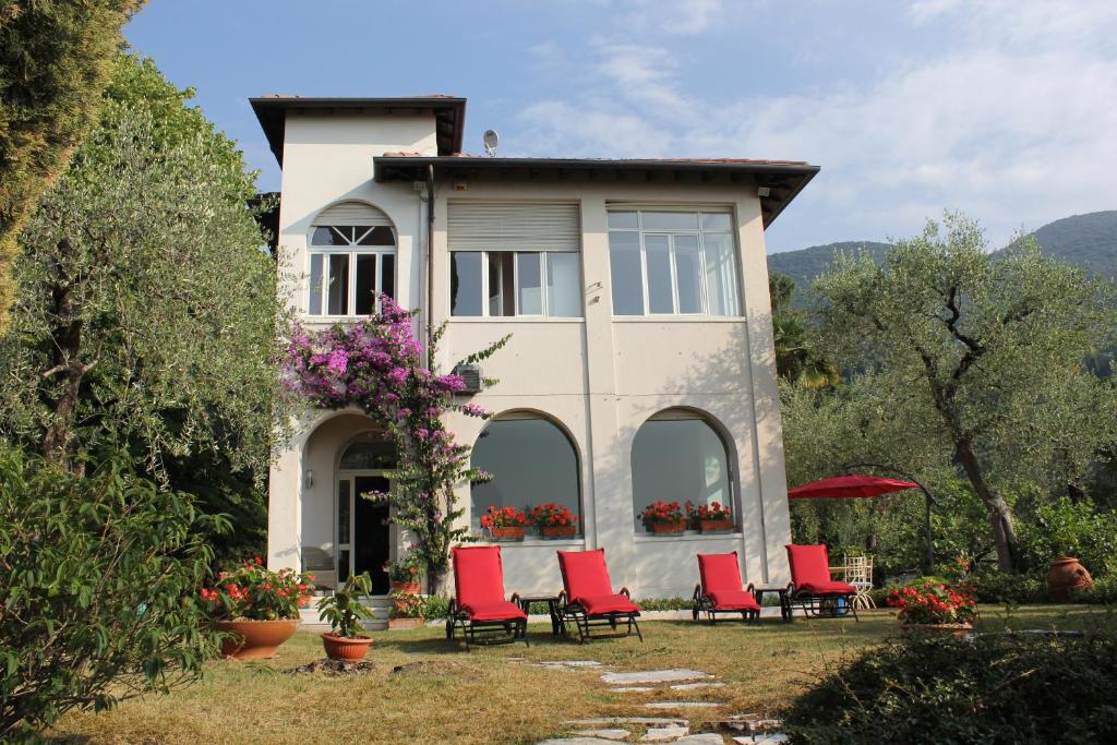 uma casa com cadeiras vermelhas em frente em Villa Serendipità em Gardone Riviera