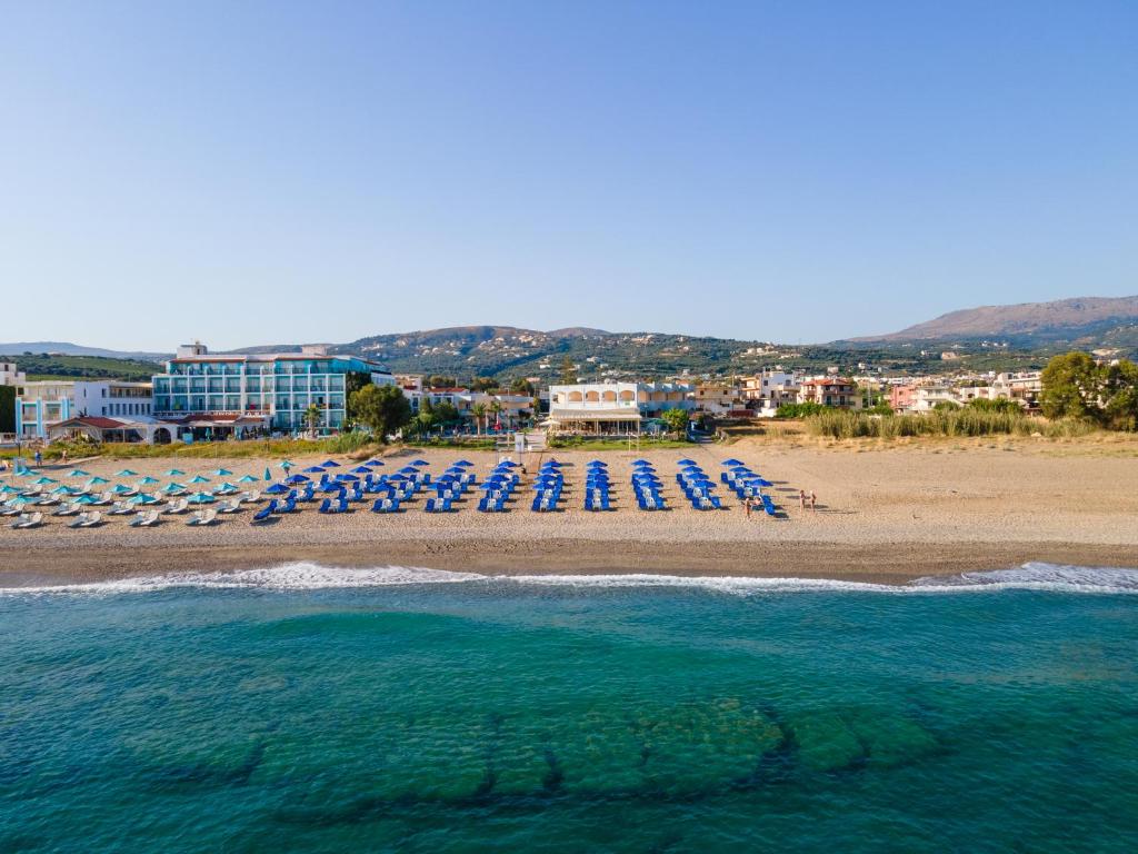 a beach with lounge chairs and the ocean at Hotel Kathrin Beach in Adelianos Kampos