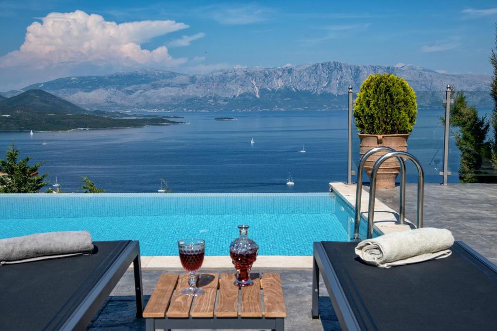 a pool with a table with two glasses of wine at Ionian Heaven Villas in Nikiana
