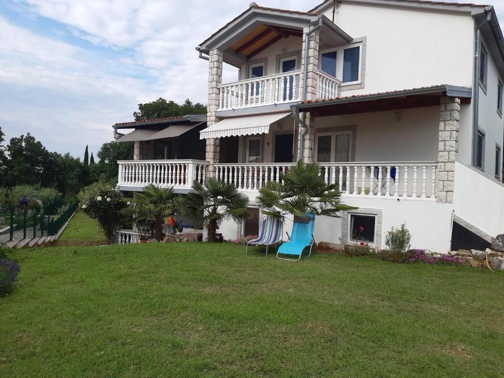 ein großes weißes Haus mit einem Hof mit zwei Stühlen in der Unterkunft Apartmani Franka in Rovinjsko Selo