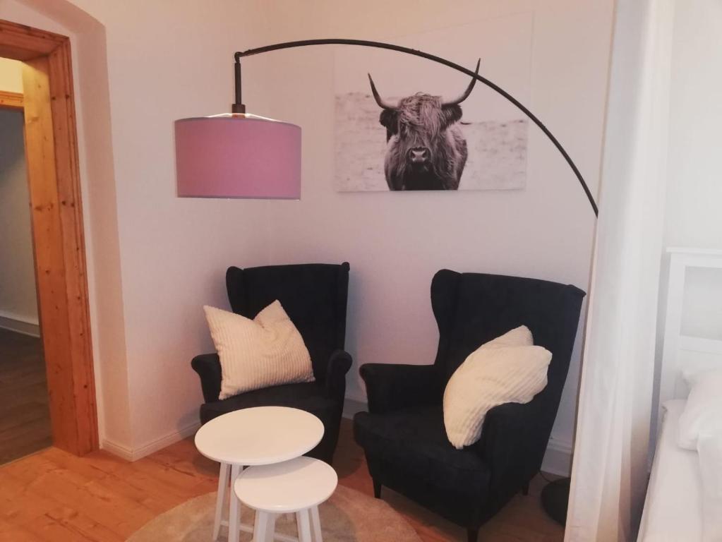 ein Zimmer mit zwei Stühlen und einem Stier an der Wand in der Unterkunft Ferienwohnung "Kleiner OTTO" in Erfurt