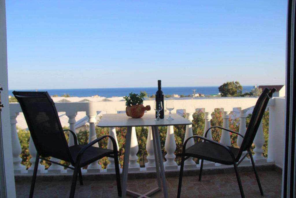 a table with a bottle of wine and two chairs at KOYNTOYRA ROOMS in Kountoura Selino