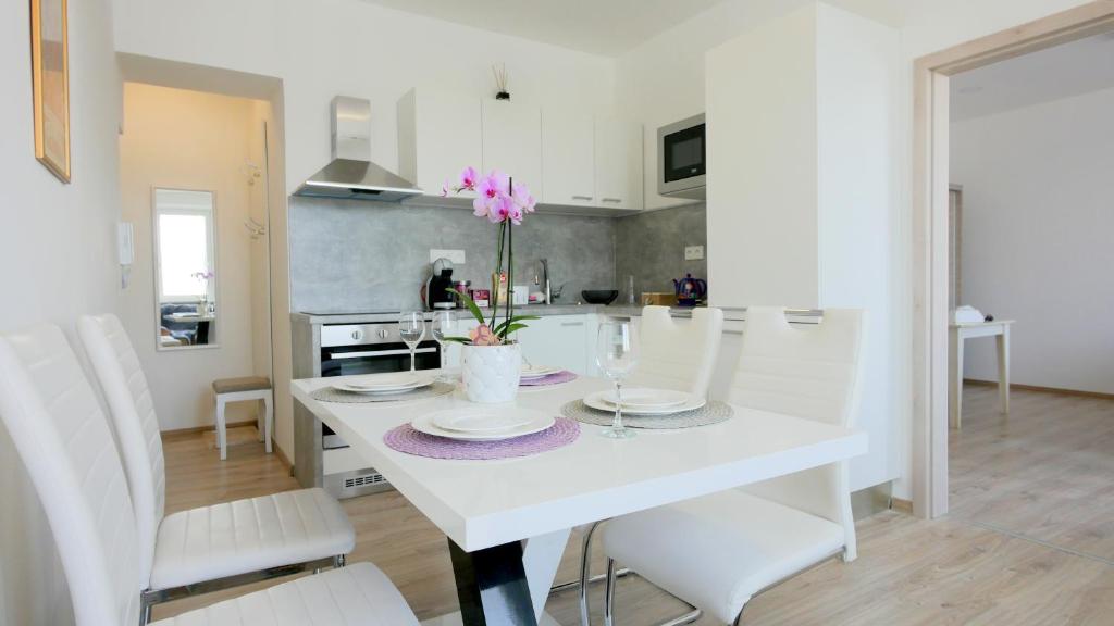 a white kitchen with a white table and white chairs at Soukromý - plně vybavený byt 2+KK in Znojmo