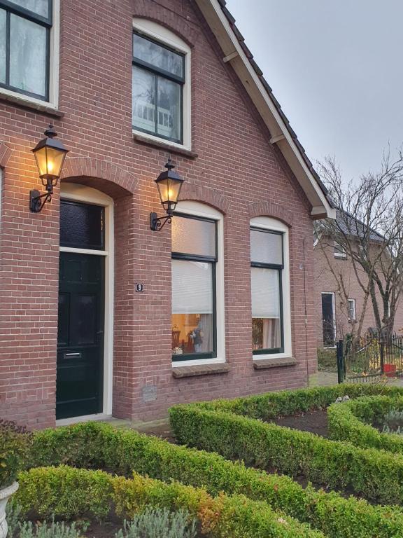 une maison en briques avec des lumières sur son côté dans l'établissement Studio in rietgedekte boerderij, geheel privé, hond vriendelijk, à Westerbork