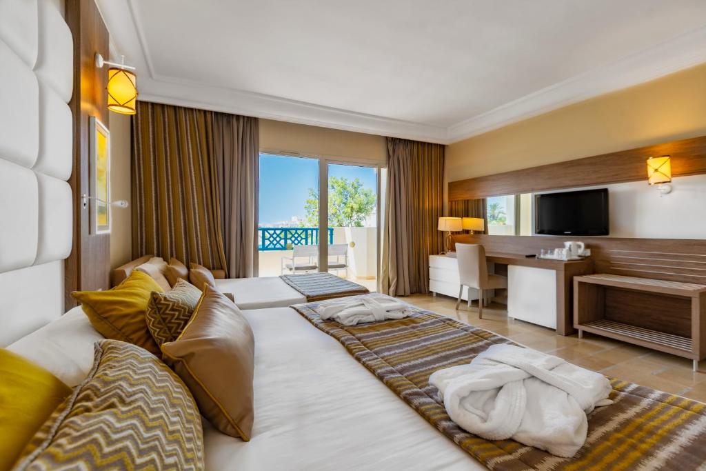 a hotel room with two beds and a desk at Sentido Bellevue Park in Port El Kantaoui