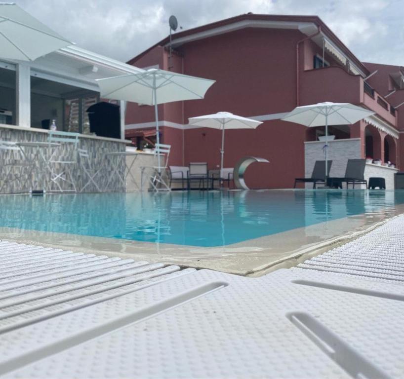 a swimming pool with chairs and umbrellas next to a building at B&B Villa Fabrizia in Diamante