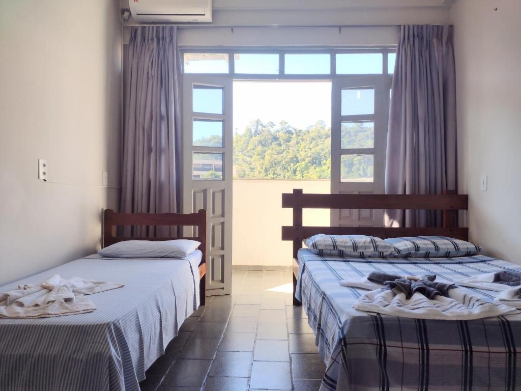 two beds in a room with a window at Hotel Santa Terezinha in Alfredo Chaves