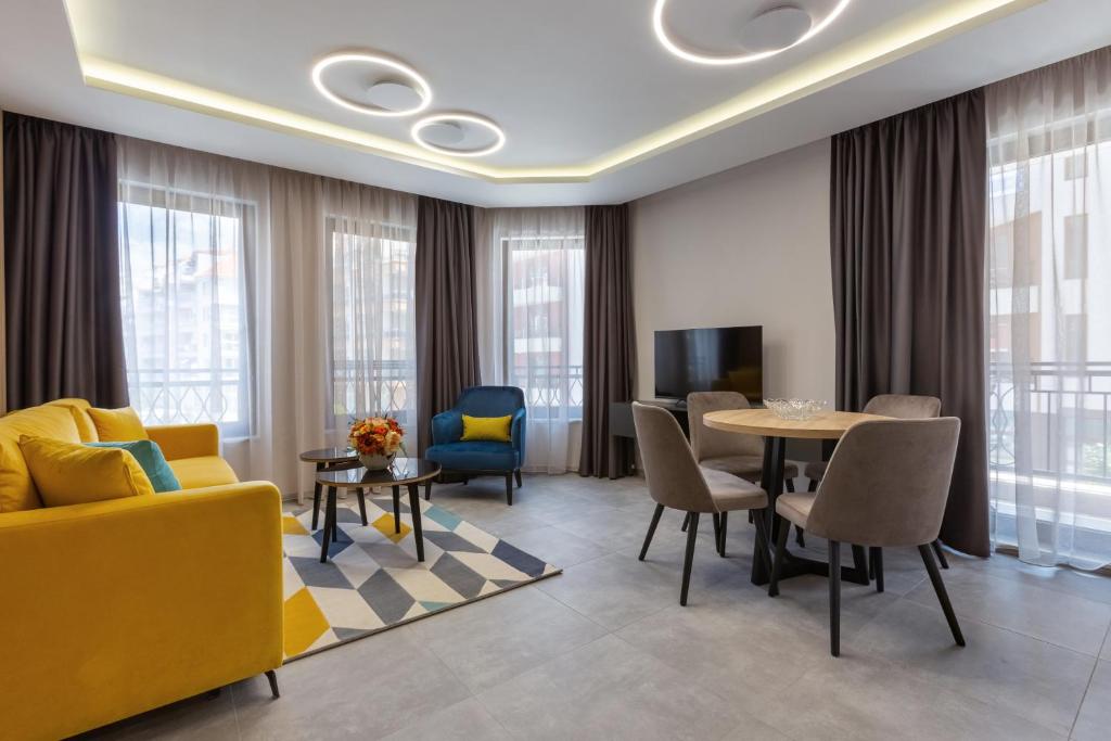 sala de estar con sofá amarillo y mesa en Inter Holiday Apartments en Pomorie