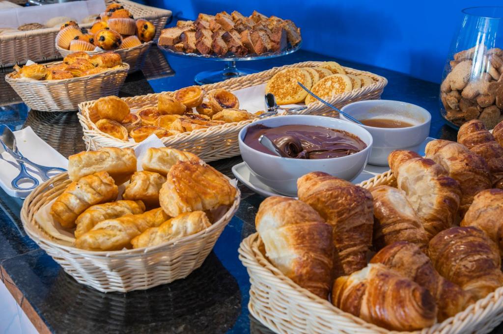 a table with baskets of bread and pastries on it at Vale d'El Rei Hotel & Villas in Carvoeiro