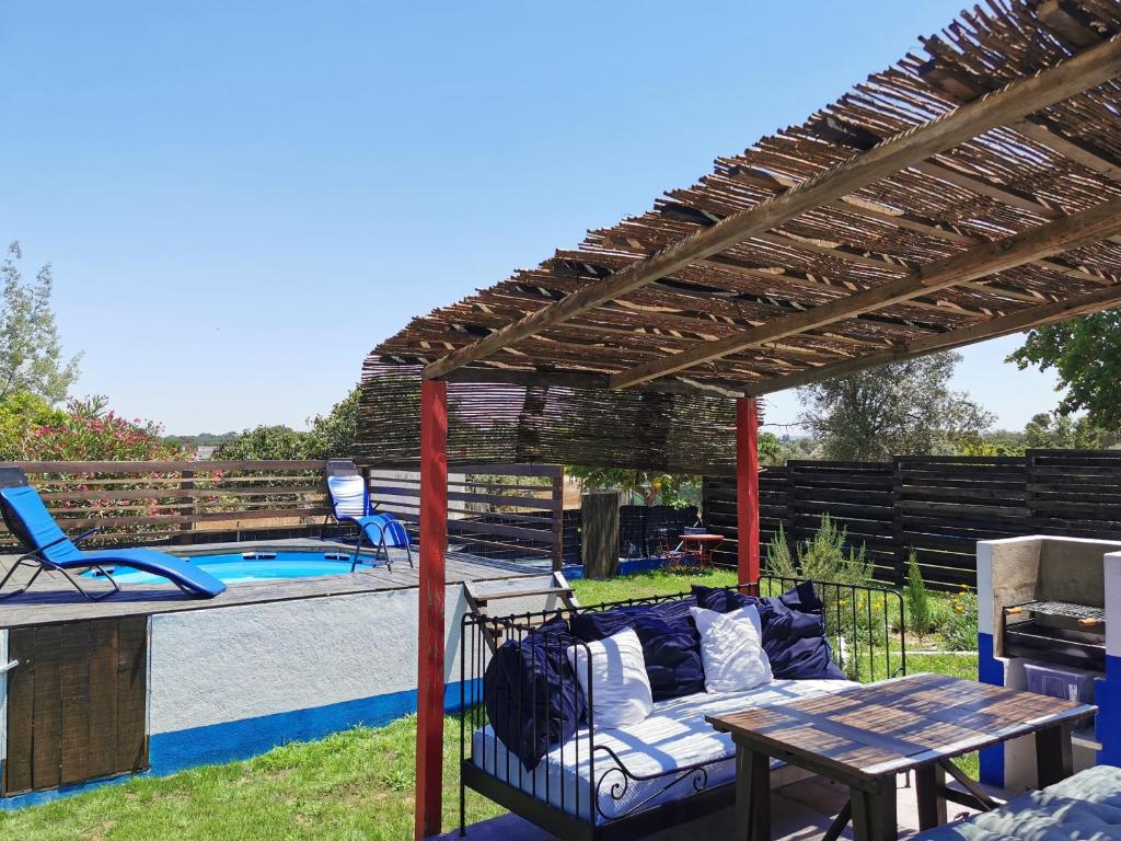 pérgola con sofá y mesa junto a la piscina en HERDADE PALMA t1, en Moita