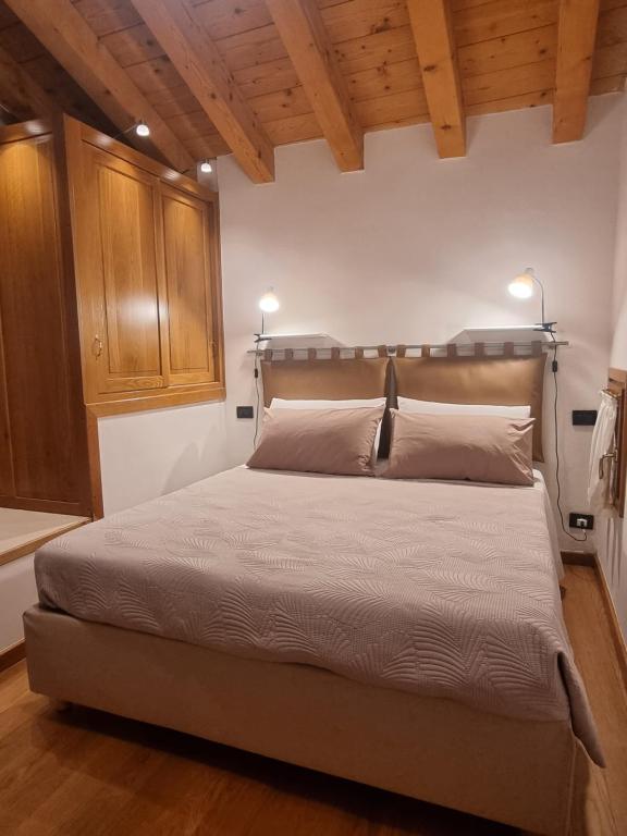 duże łóżko w pokoju z drewnianymi sufitami w obiekcie Giulietta e Romeo w mieście Pove del Grappa