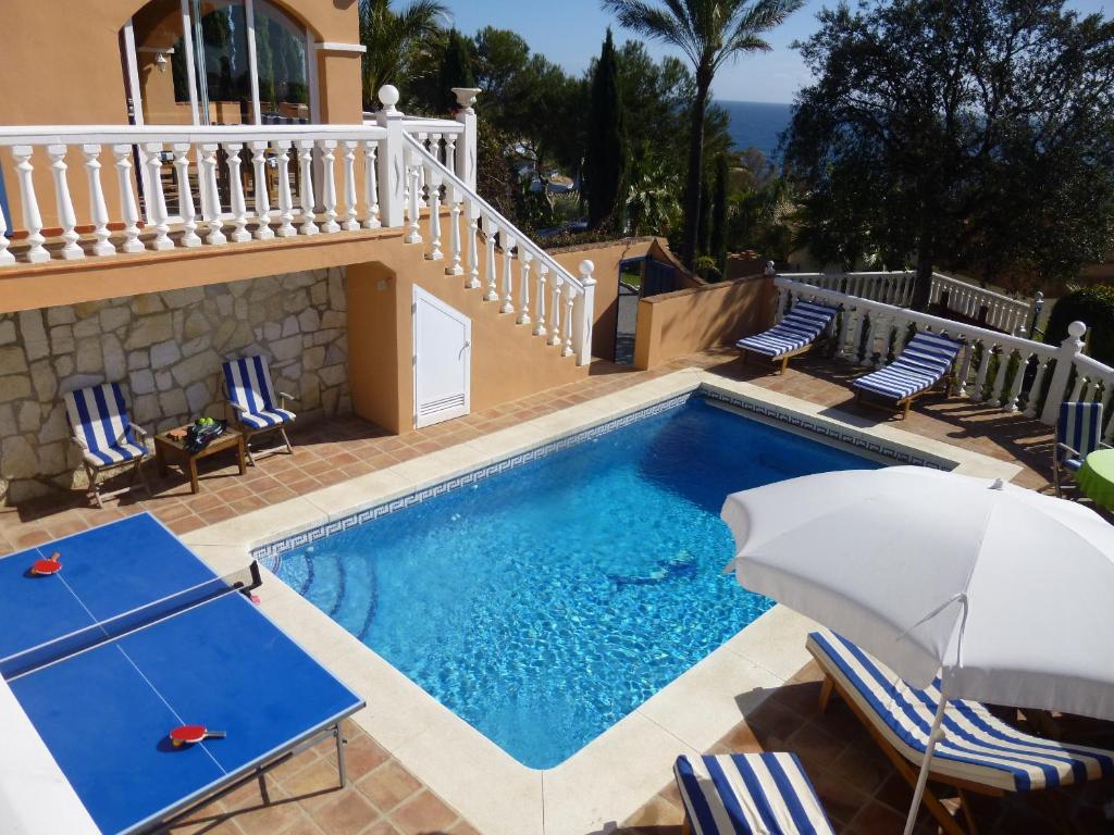 basen z krzesłami i parasolem obok domu w obiekcie Casa Alexandra w mieście La Cala de Mijas