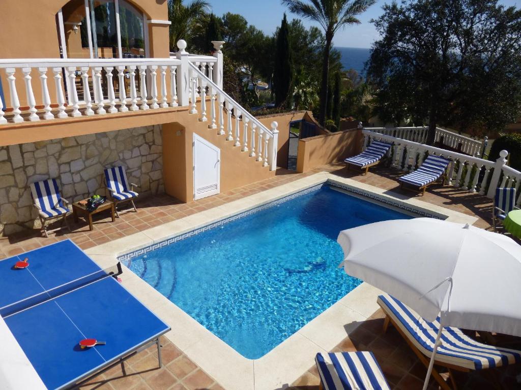 a pool with chairs and an umbrella next to a house at Casa Alexandro in La Cala de Mijas