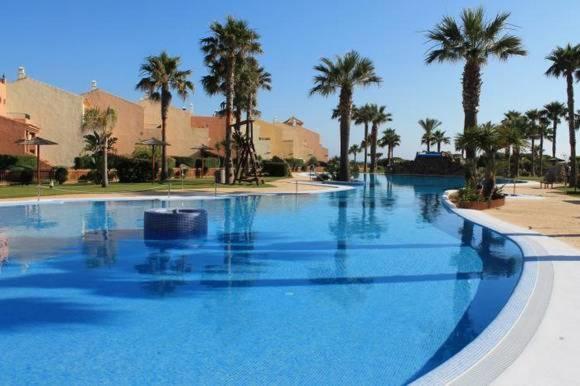 een groot zwembad met palmbomen in een resort bij APARTAMENTO ZAHARA DE LOS ATUNES in Zahara de los Atunes
