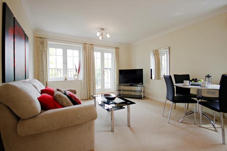 a living room with a couch and a table at Sunny 1 bed apartment in a quiet central location in Basingstoke