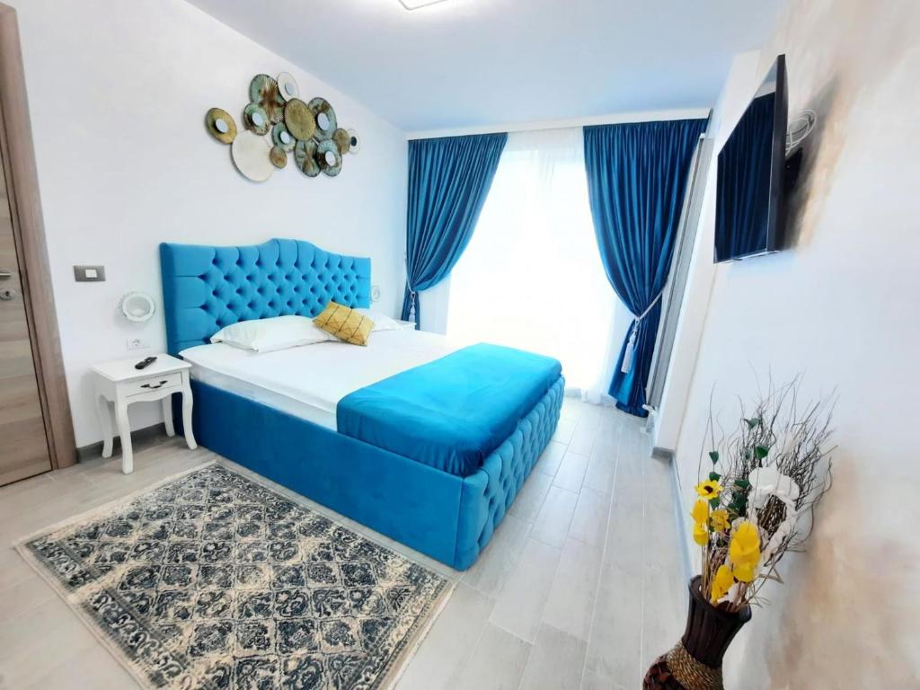 1 dormitorio con cama azul y cortinas azules en Apartament Rebeca Lux by Alezzi Beach Resort, en Mamaia Nord – Năvodari
