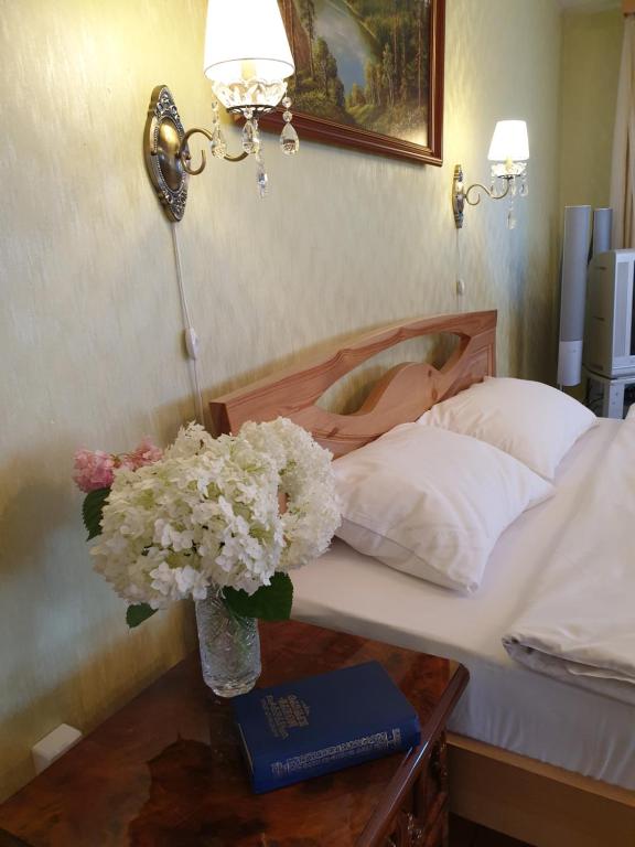 a bed with a vase of flowers on a table at Pokrovsky Guest House in Suzdal