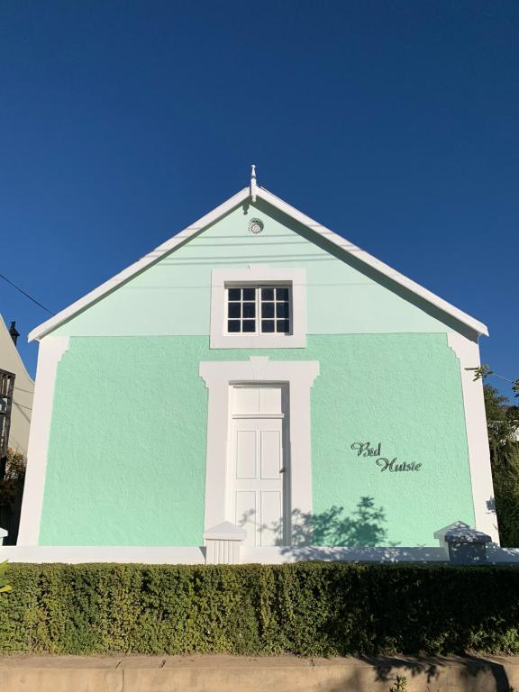 een blauw-wit gebouw met een witte deur bij Bidhuisie in Prince Albert