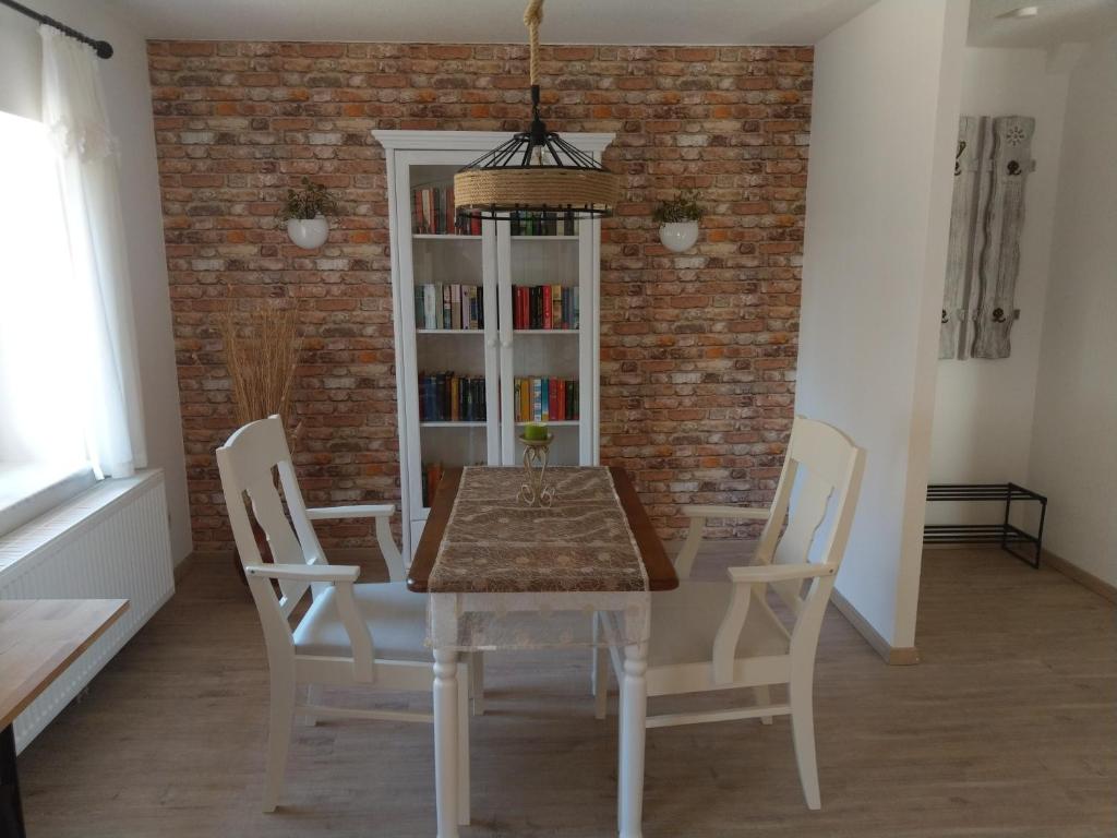 a dining room table with white chairs and a brick wall at Ferienhaus Kranichzauber in Klausdorf Mecklenburg Vorpommern