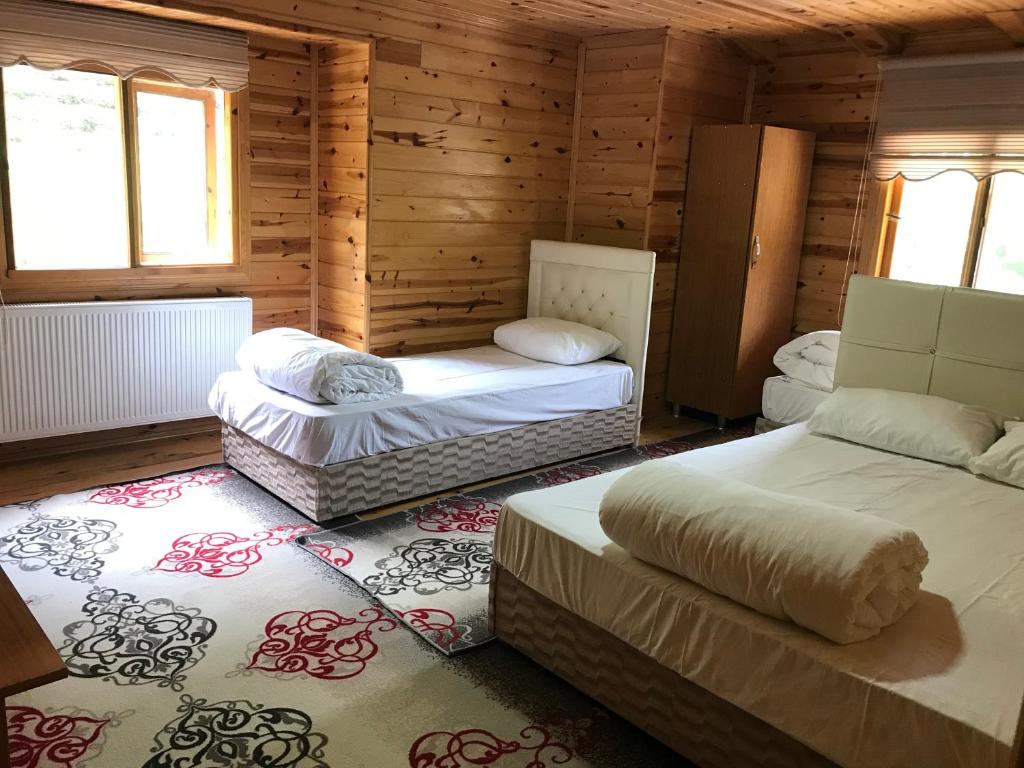 two beds in a room with wooden walls and windows at Irmak Apart in Çamlıhemşin